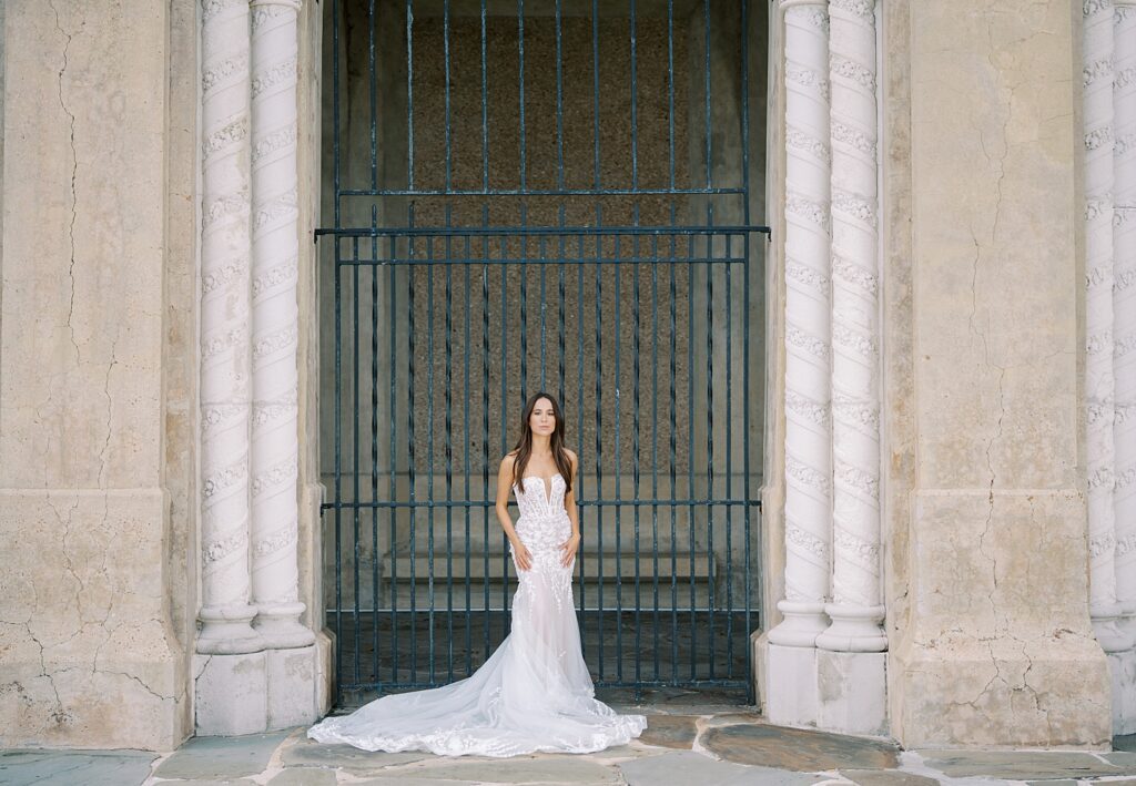 bride stands in front of green metal gate at Hollis Gardens