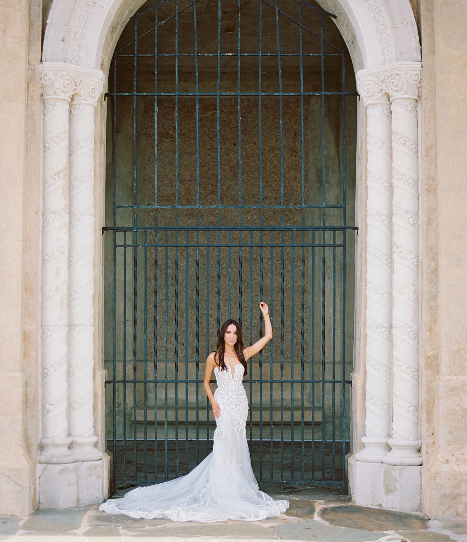bride poses in front of green gate inside Hollis Gardens