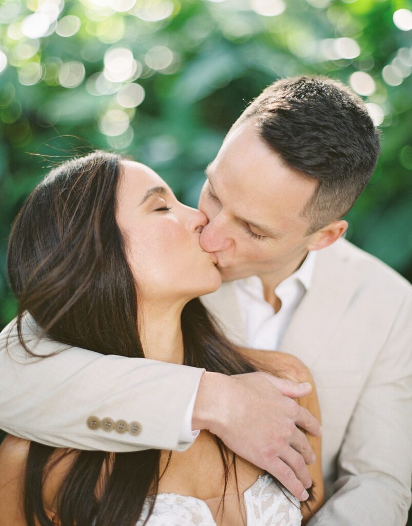 man hugs woman from behind kissing her inside Hollis Gardens