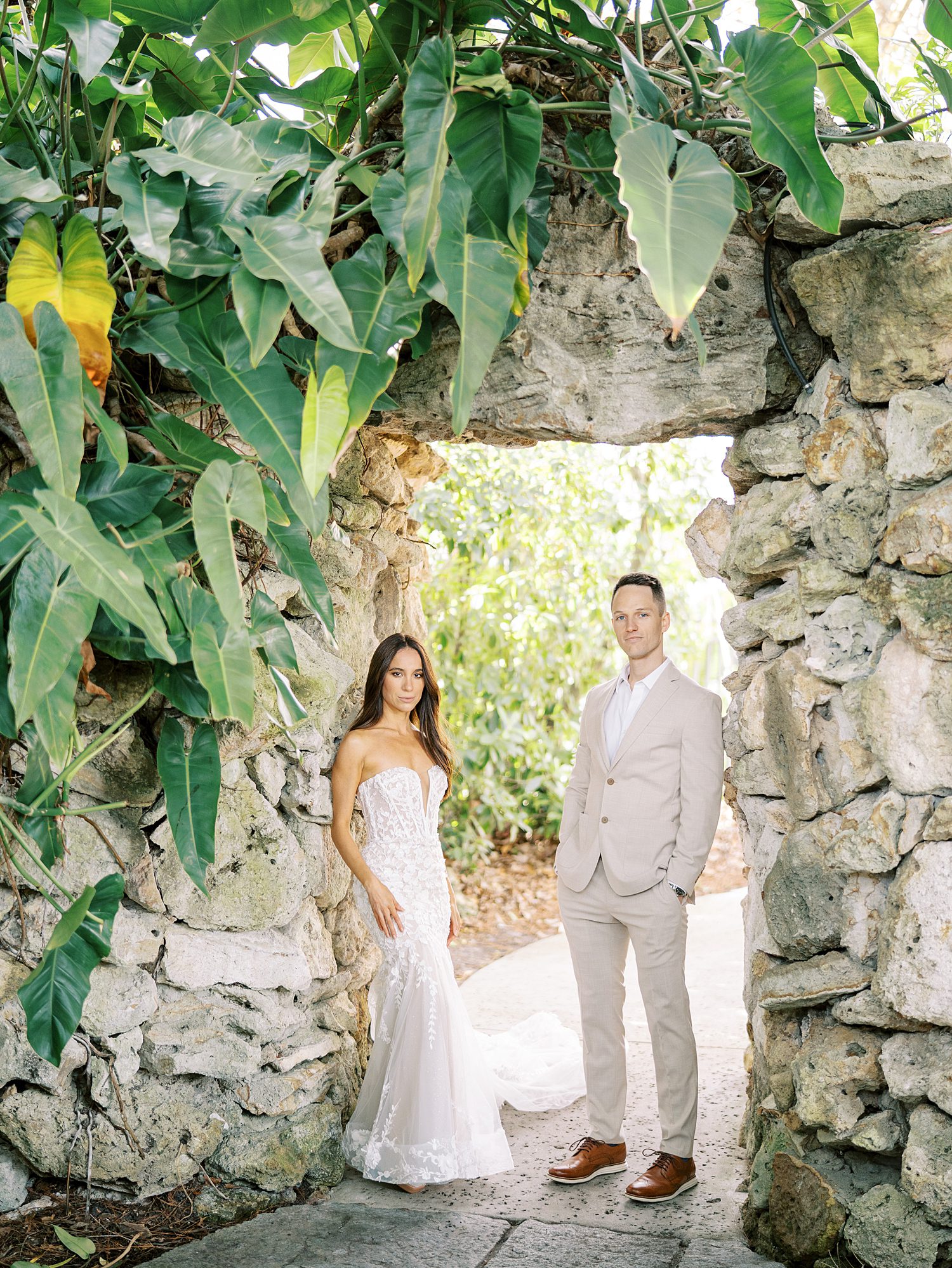 husband and wife pose between stone archway at Hollis Gardens