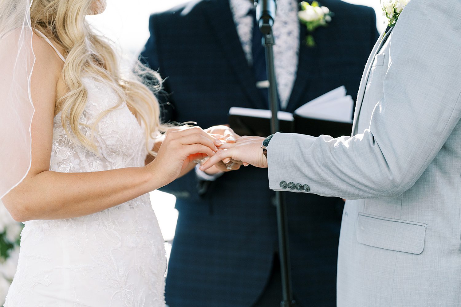 bride slips ring on groom's hand during rooftop wedding ceremony at Armature Works