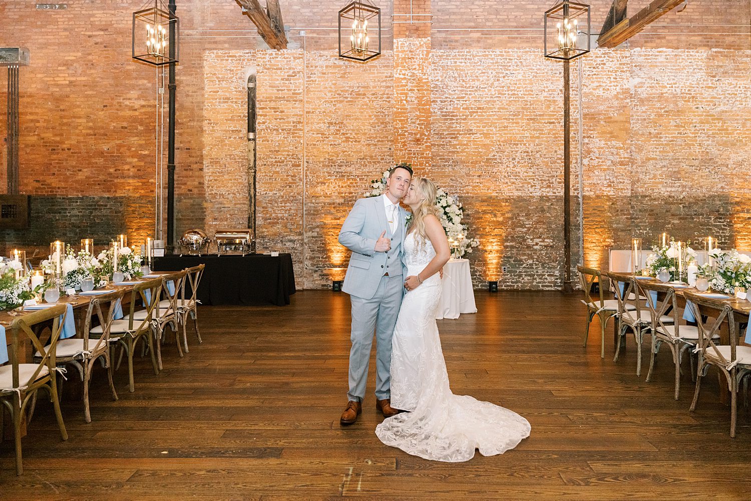 bride leans to kiss groom's cheek in reception space at Armature Works