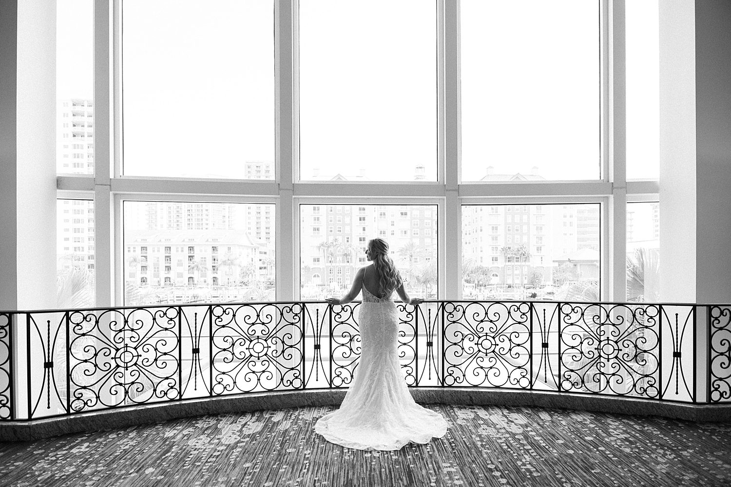 bride stands looking out window from balcony inside Armature Works