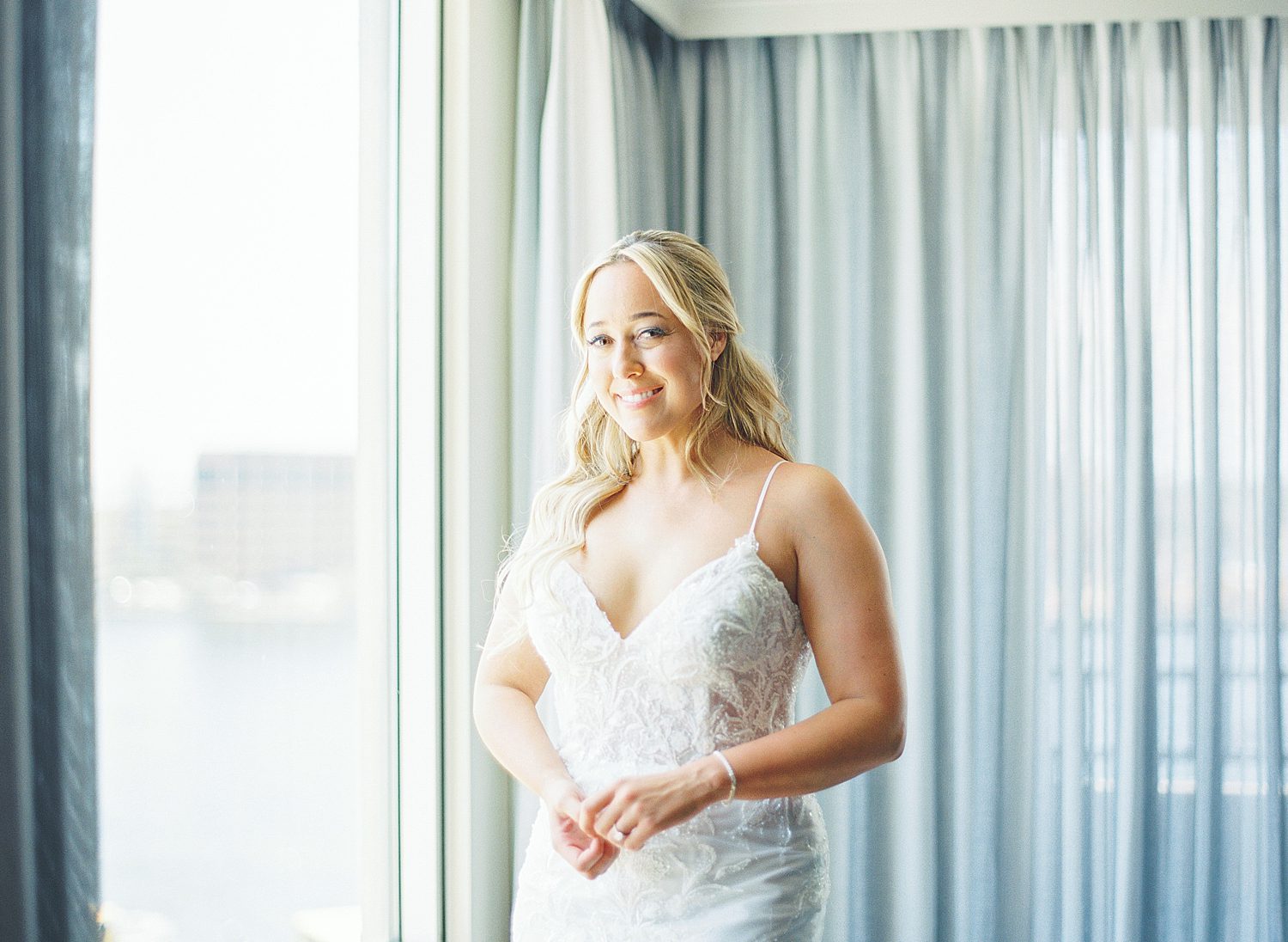 bride smiles in strapless wedding gown by blue curtains in Tampa Marriott hotel