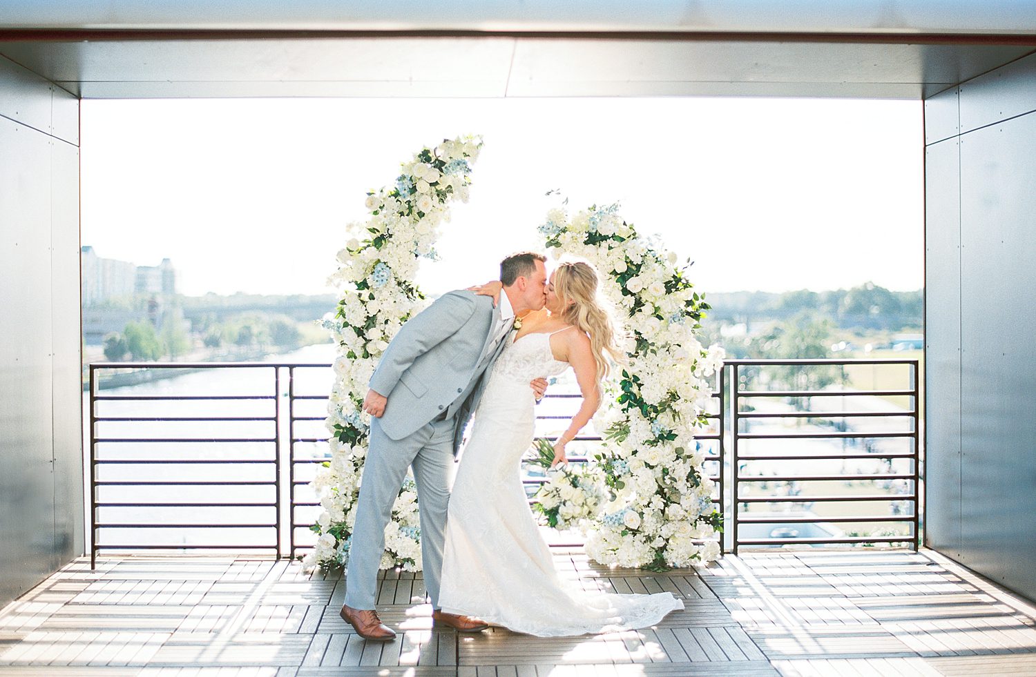 groom kisses bride while she holds bouquet behind her
