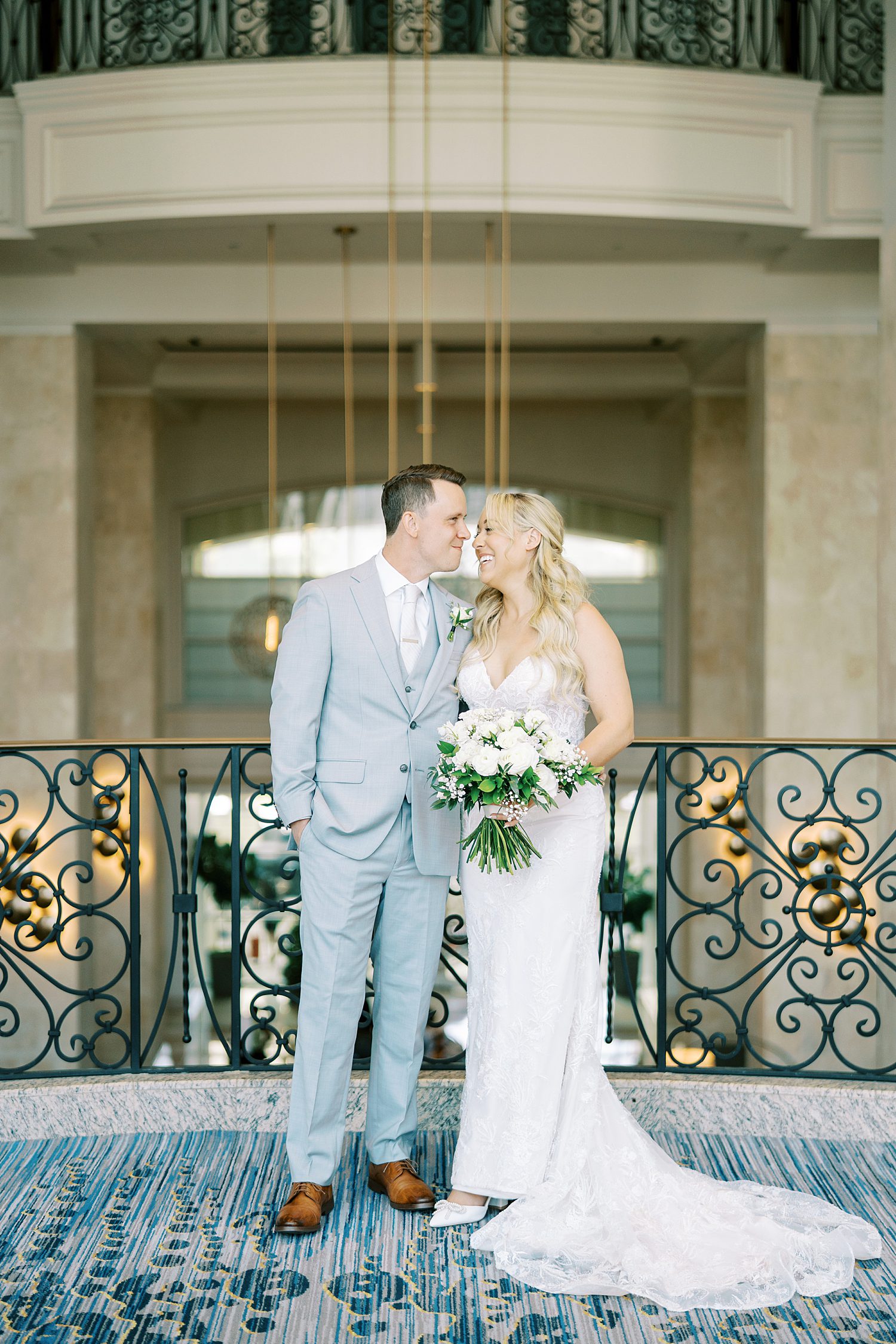 newlyweds smile at each other leaning heads together in front of metal railing