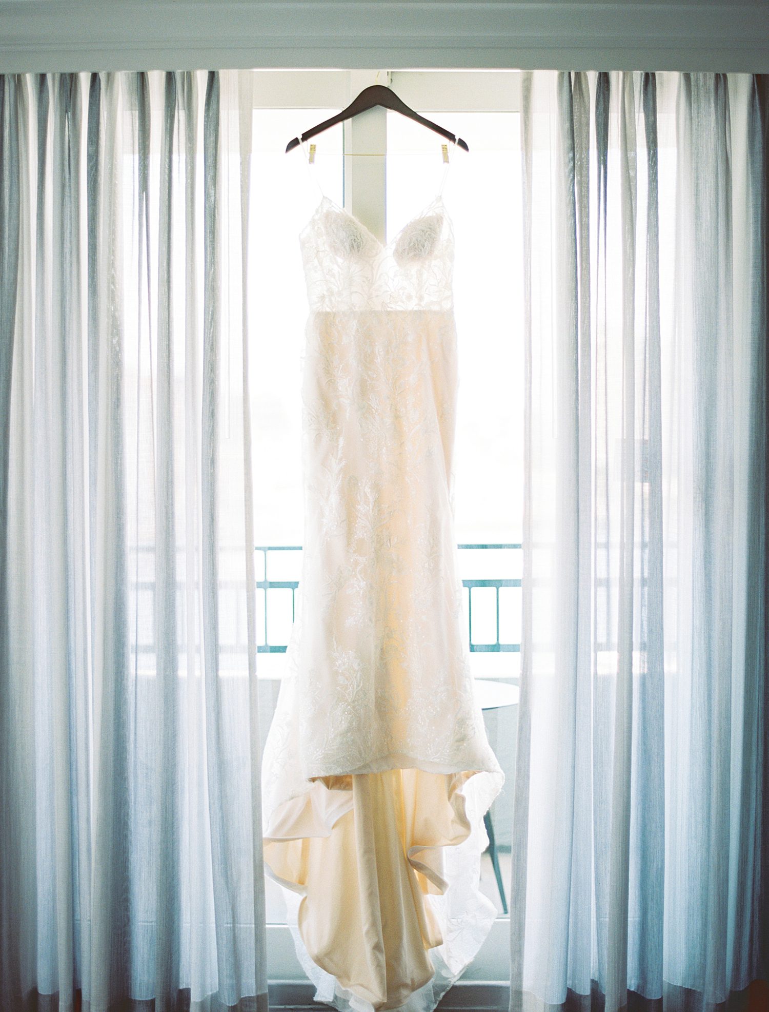 wedding dress hangs between blue curtains in hotel room in Tampa FL