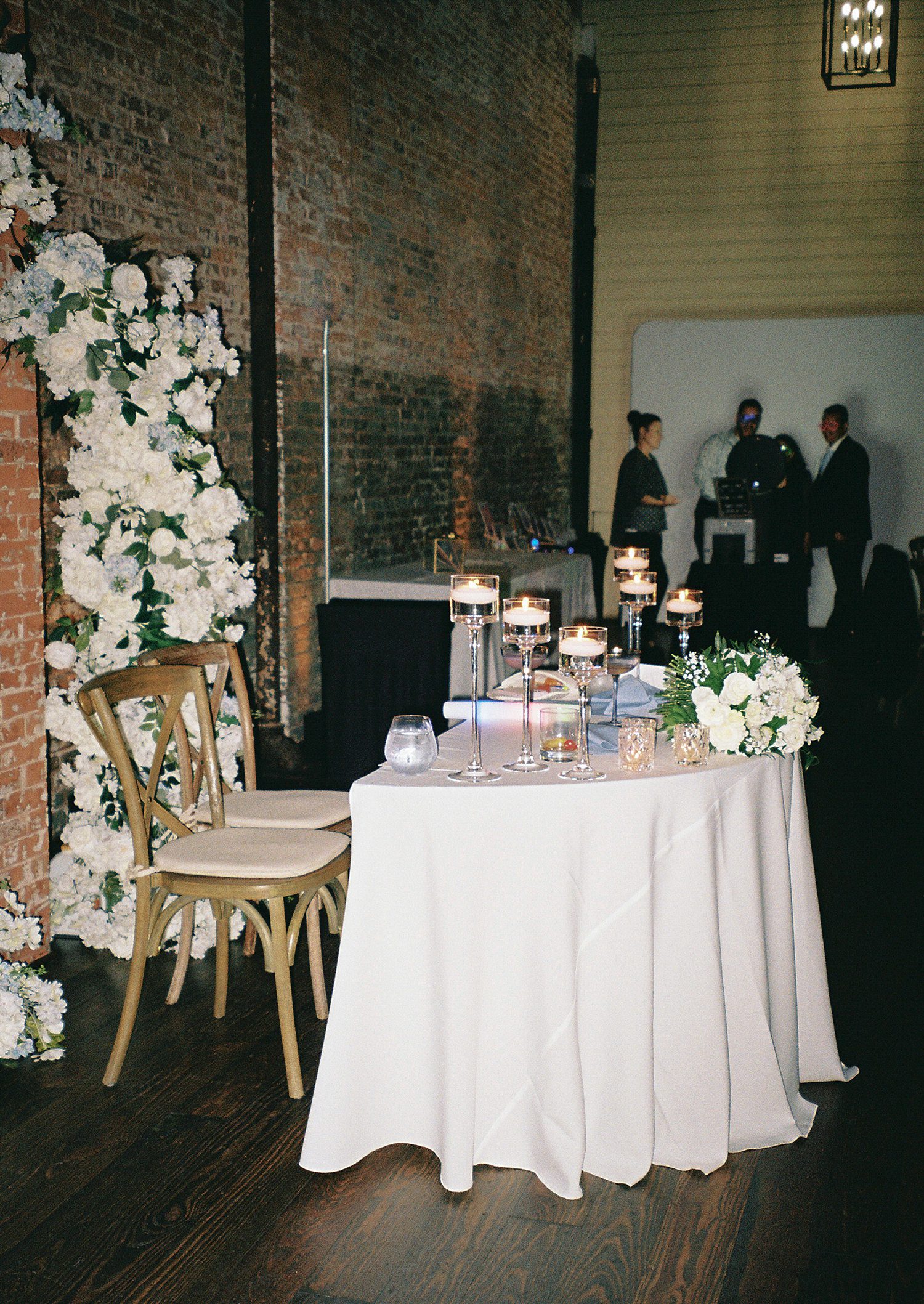 sweetheart table in front of white floral arches at Armature Works