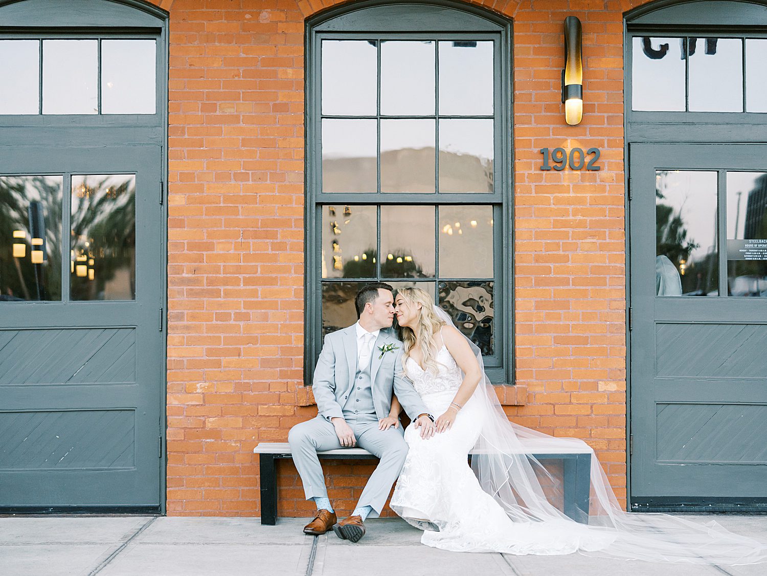 bride and groom sit in front of Armature Works on wedding day