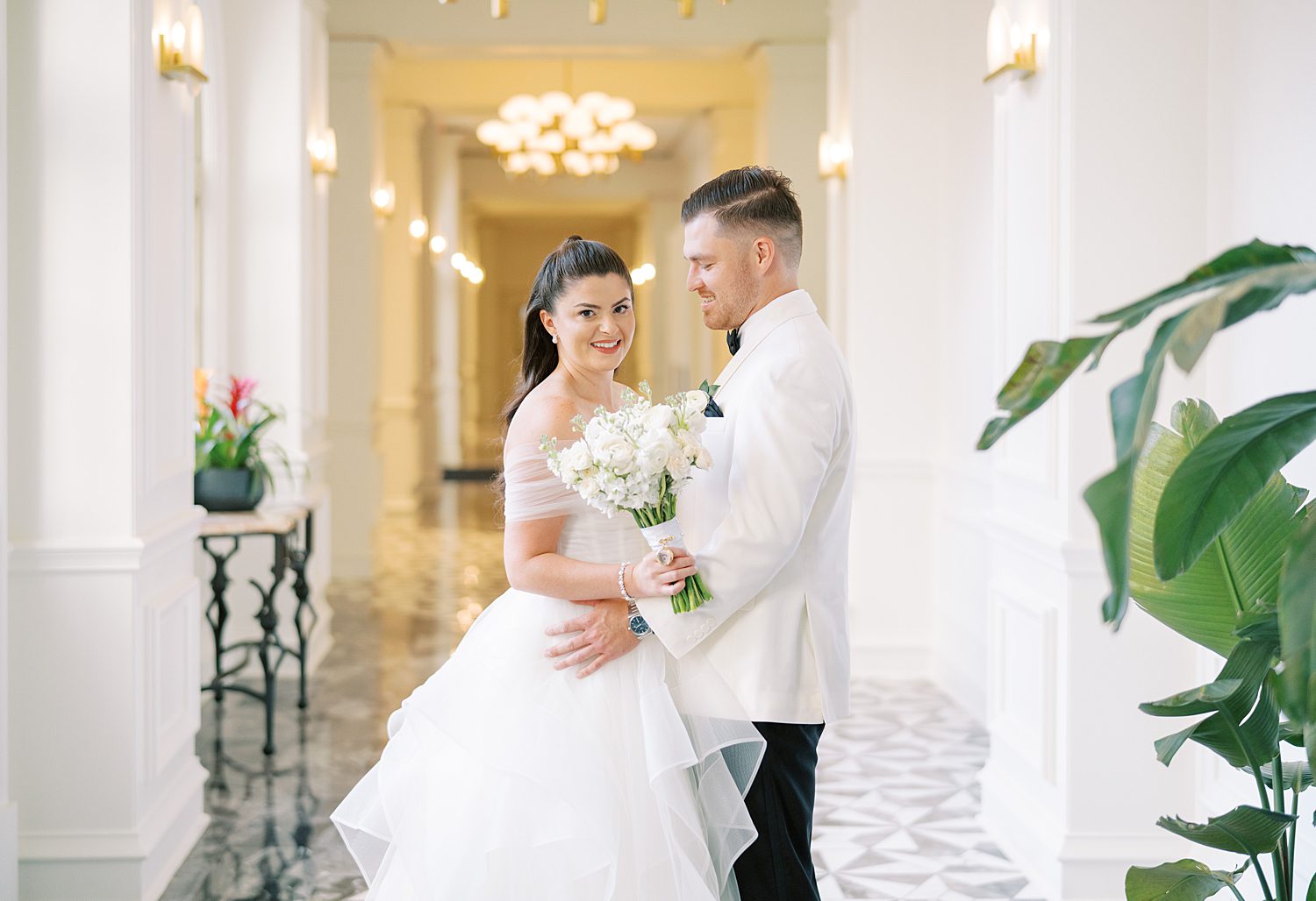 groom smiles at bride hugging her in the hallway at the Ritz Carlton Sarasota