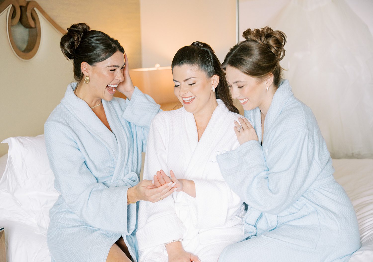 bride laughs with bridesmaids in light blue robes in Sarasota Florida