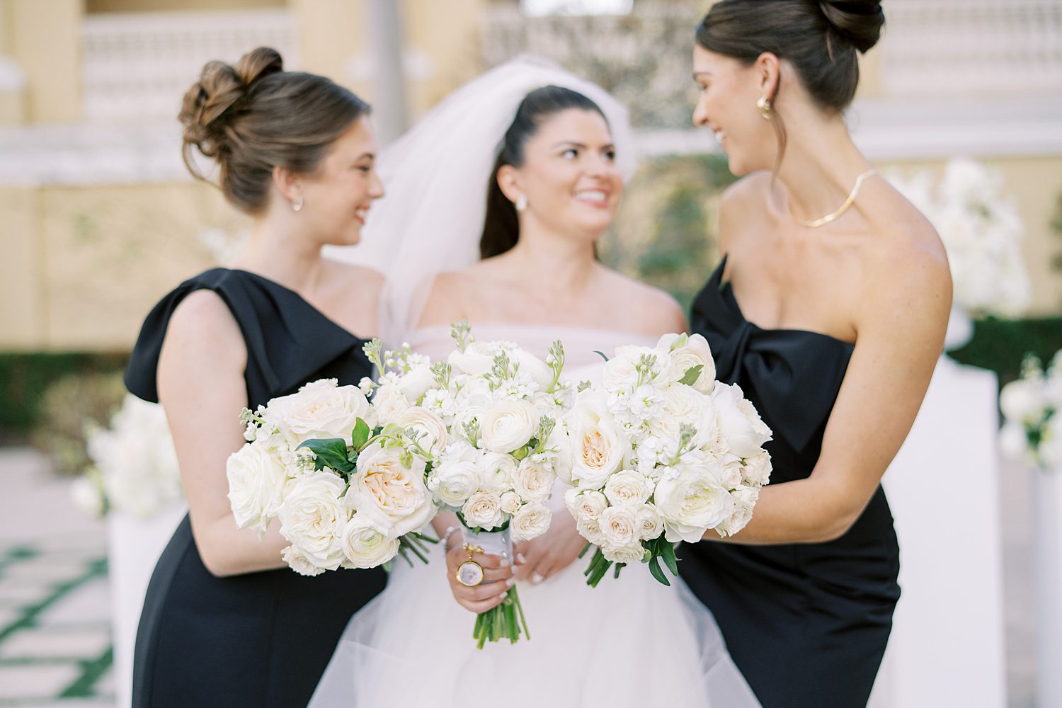 bride poses with bridesmaids in black dresses with white flowers