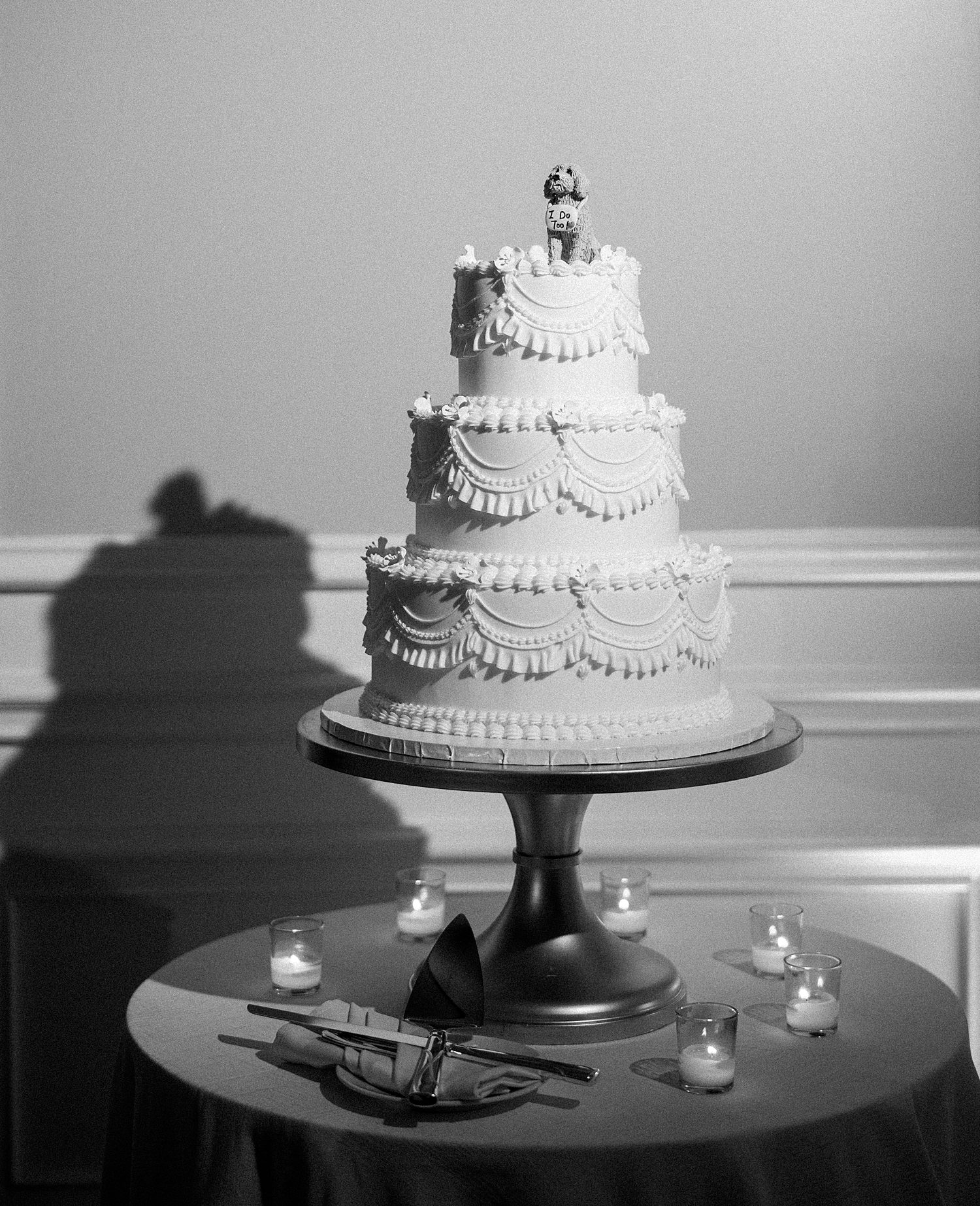 black and white photo of tiered cake with dog cake topper