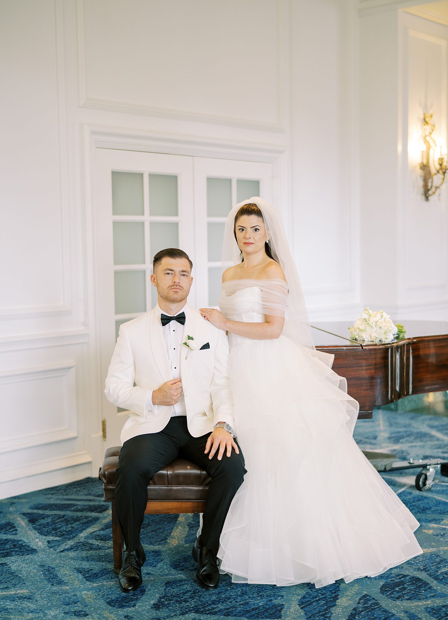 bride and groom pose by piano in lobby at the Ritz Carlton Sarasota