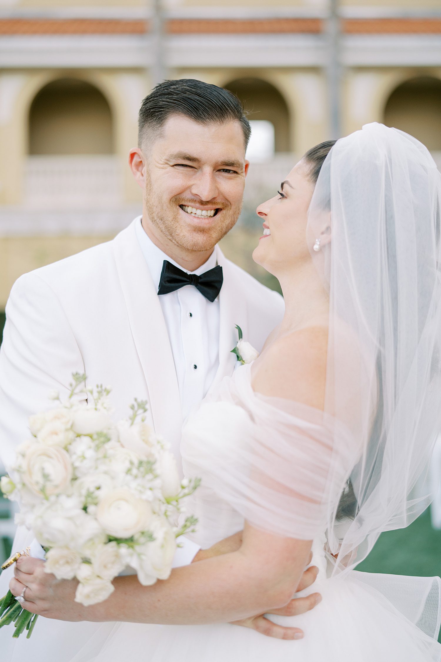 bride smiles hugging groom during wedding portraits in Florida