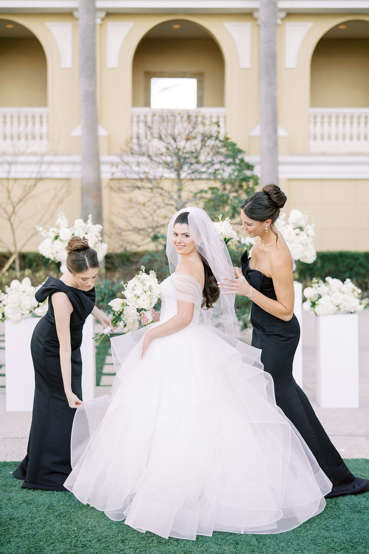 bride poses with bridesmaids in black gowns at the Ritz Carlton Sarasota