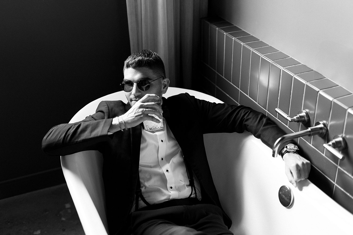 groom sits in bathtub drinking on wedding day