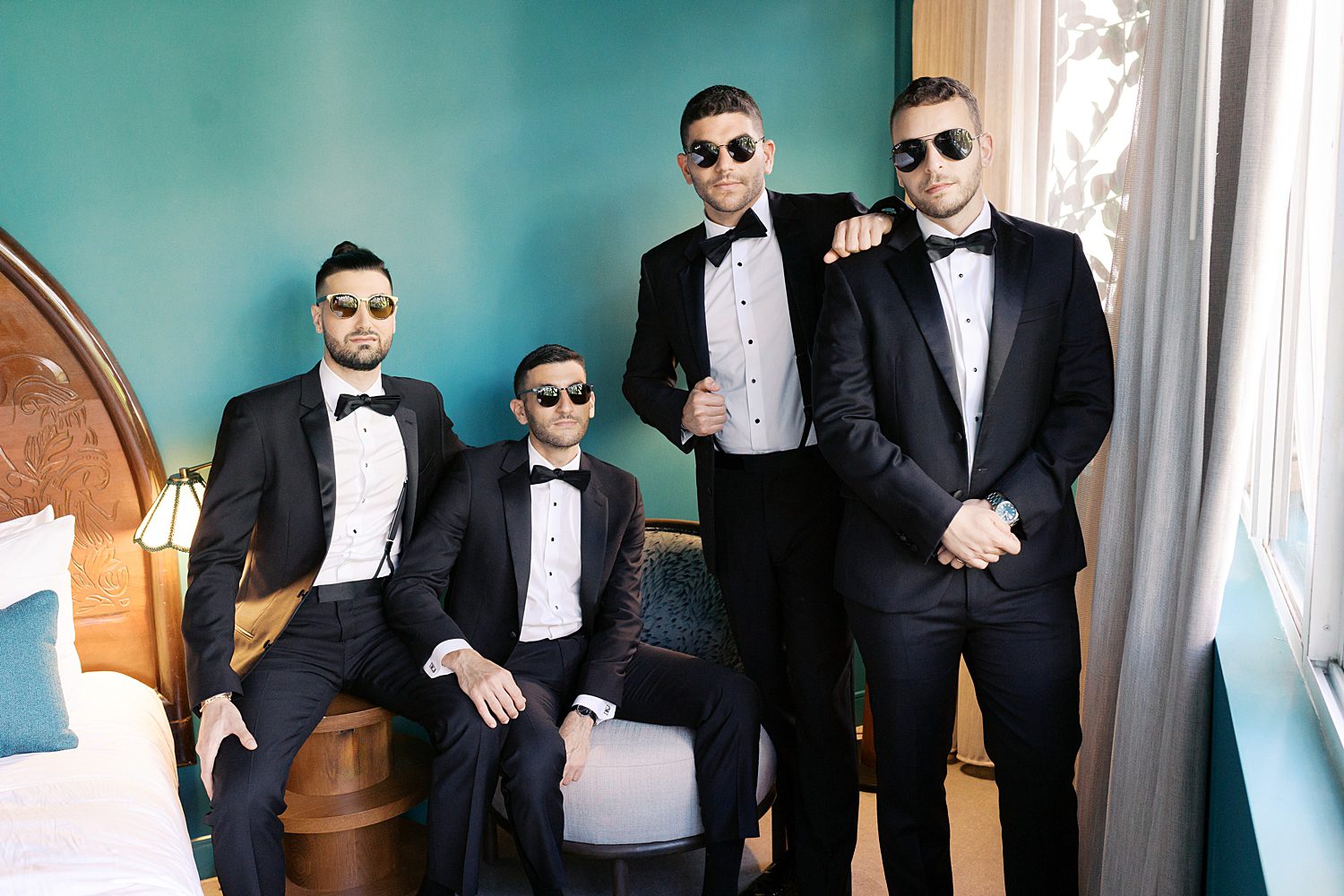 groom and groomsmen pose by teal wall at Mayfair House in Miami FL
