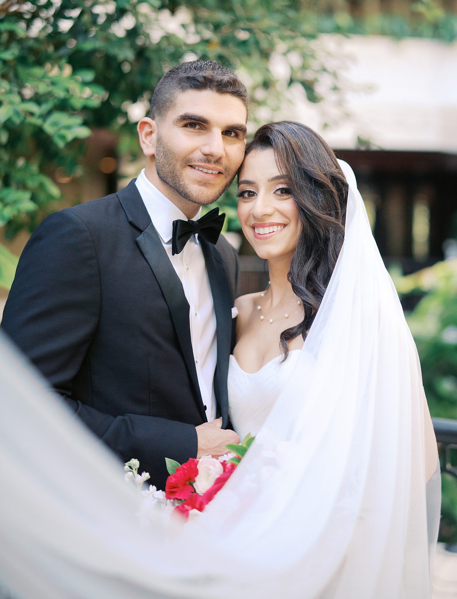 bride smiles with groom with veil pulled around them in lobby of the Mayfair House Hotel