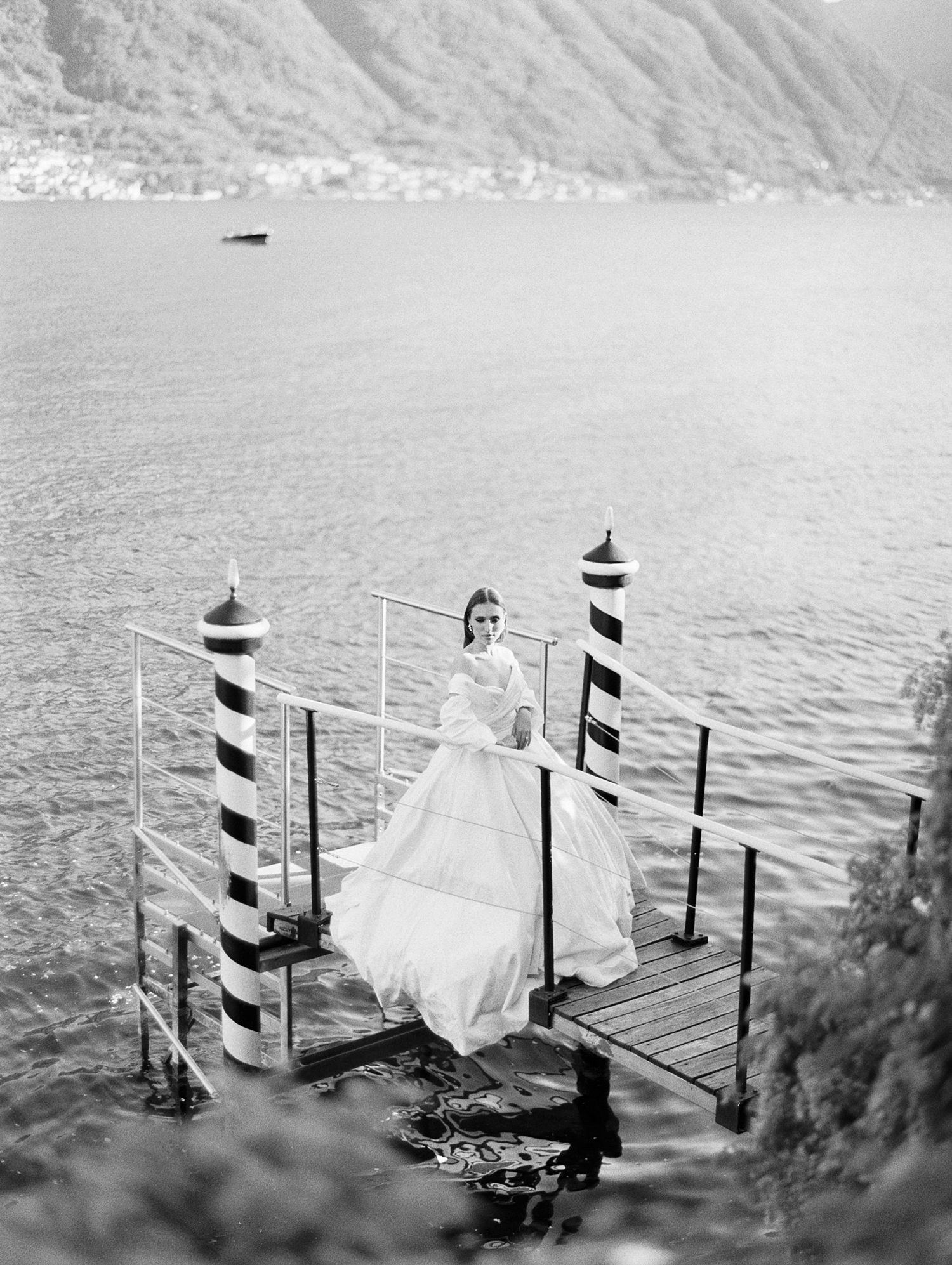 bride stands on dock on Lake Como on wedding day