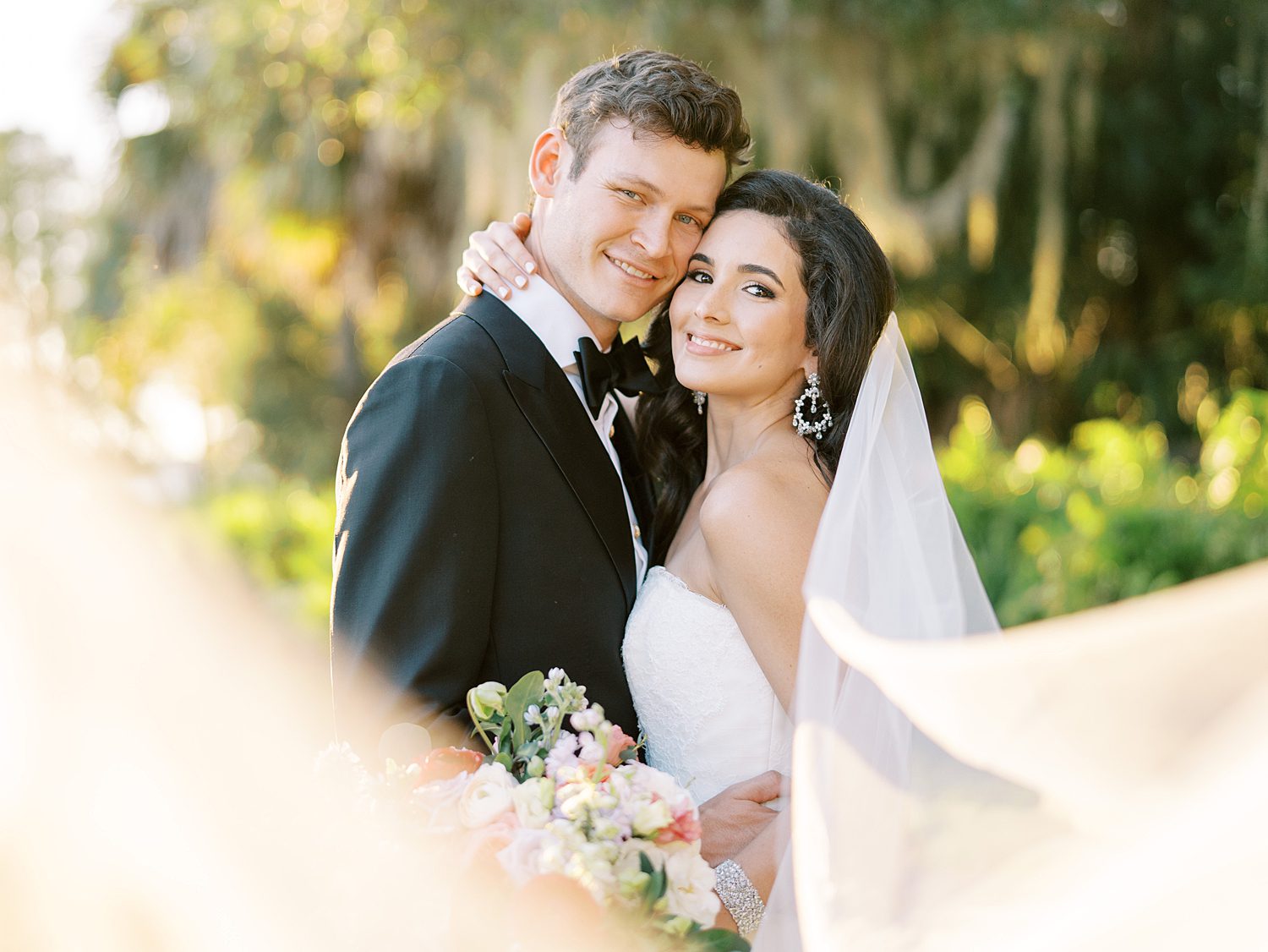 bride and groom hug with bride's veil pulled in front of them at Stonelake Ranch