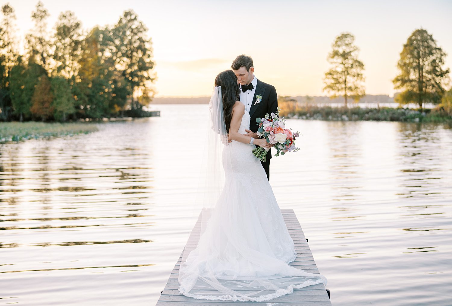 bride and groom kiss on dock at sunset at Stonelake Ranch