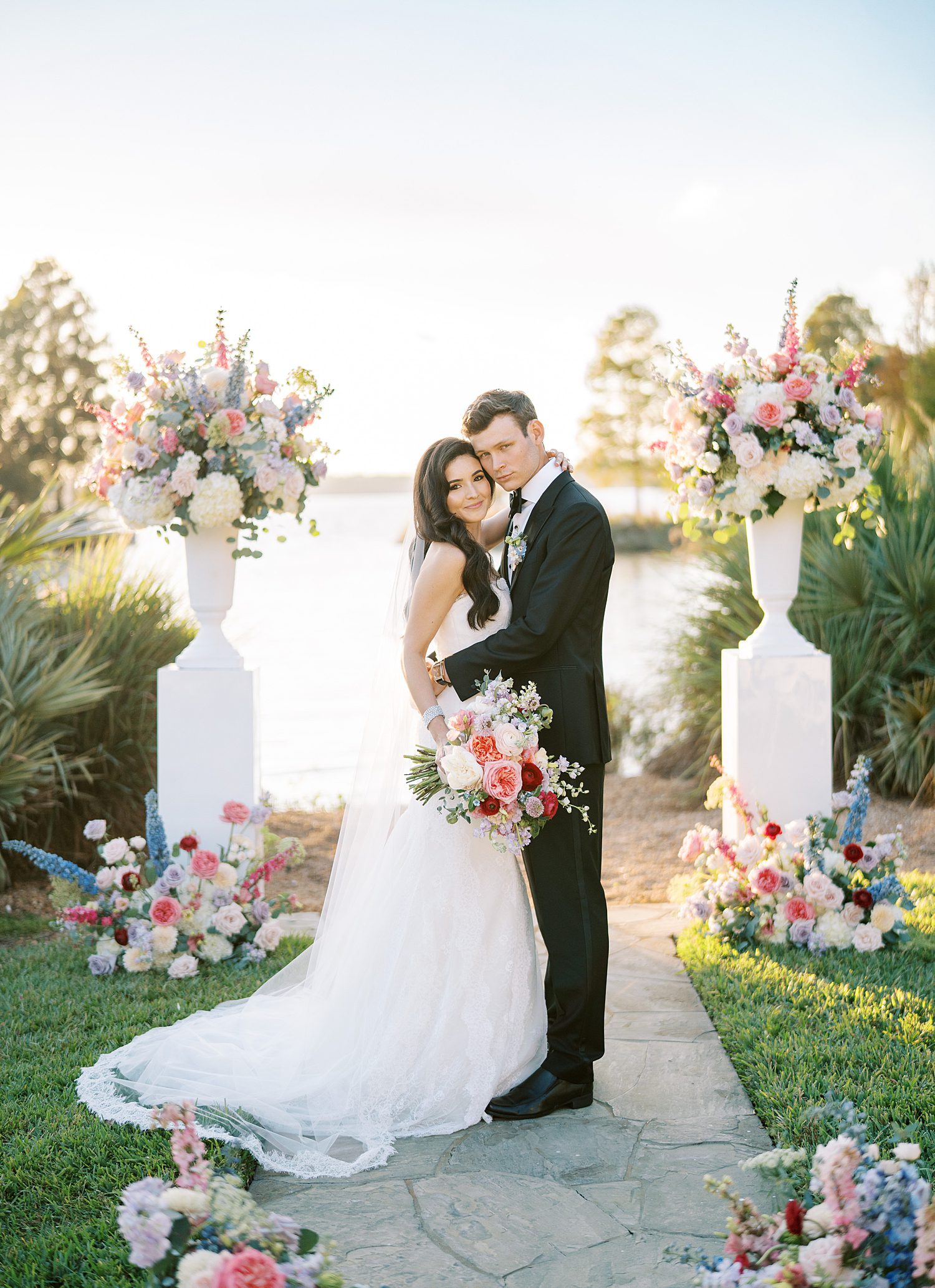 bride and groom hug at end of aisle by lake at Stonelake Ranch