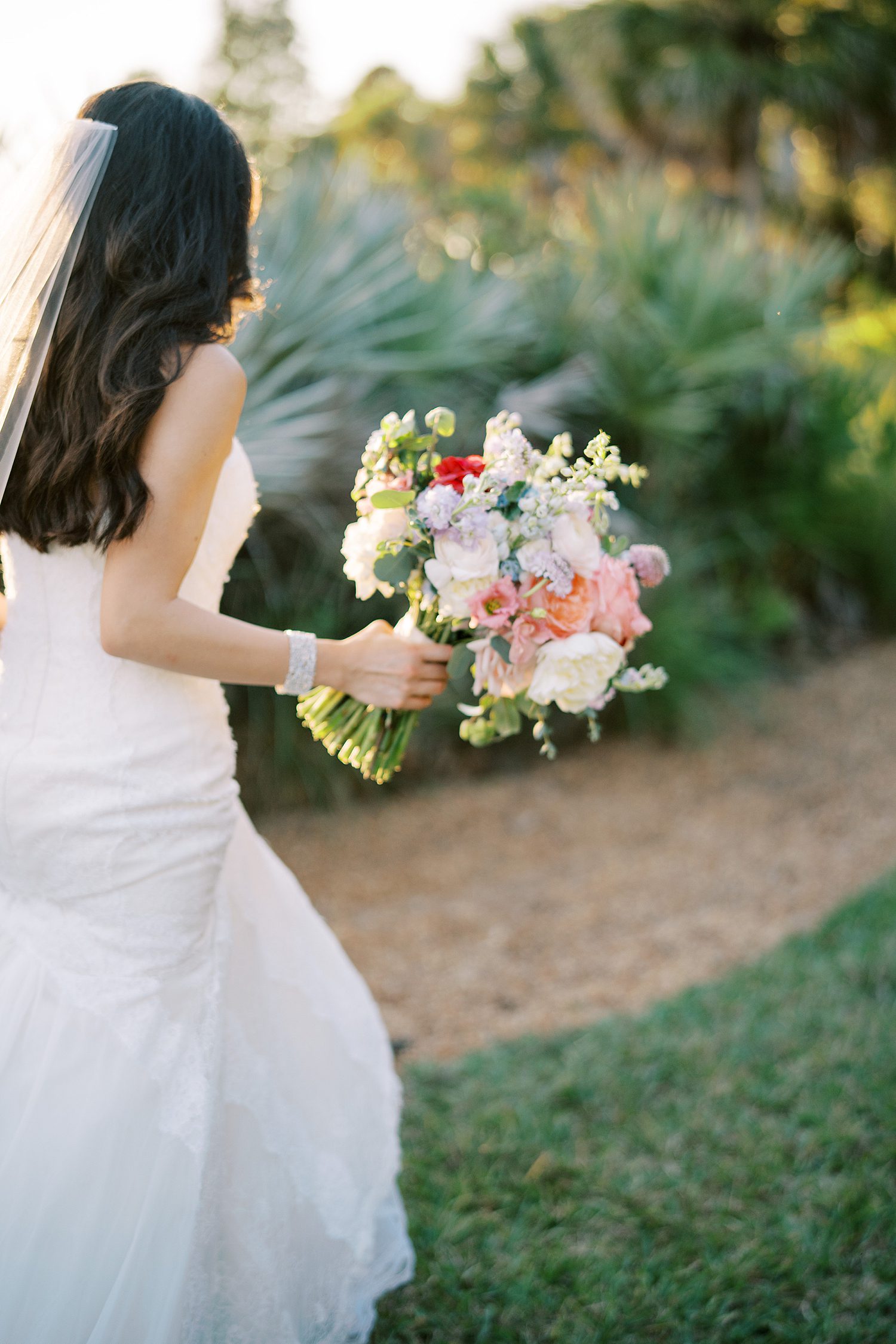 bride walks carrying bouquet of bright flowers at Stonelake Ranch