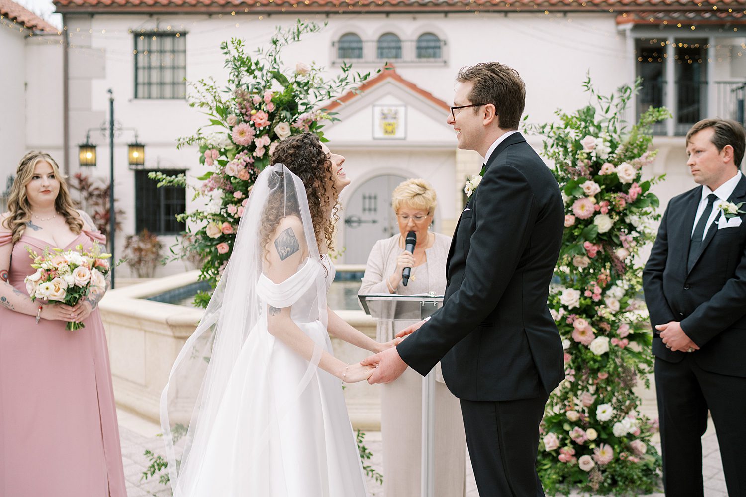 bride and groom laugh during wedding ceremony in courtyard at the Bishop Museum of Science and Nature