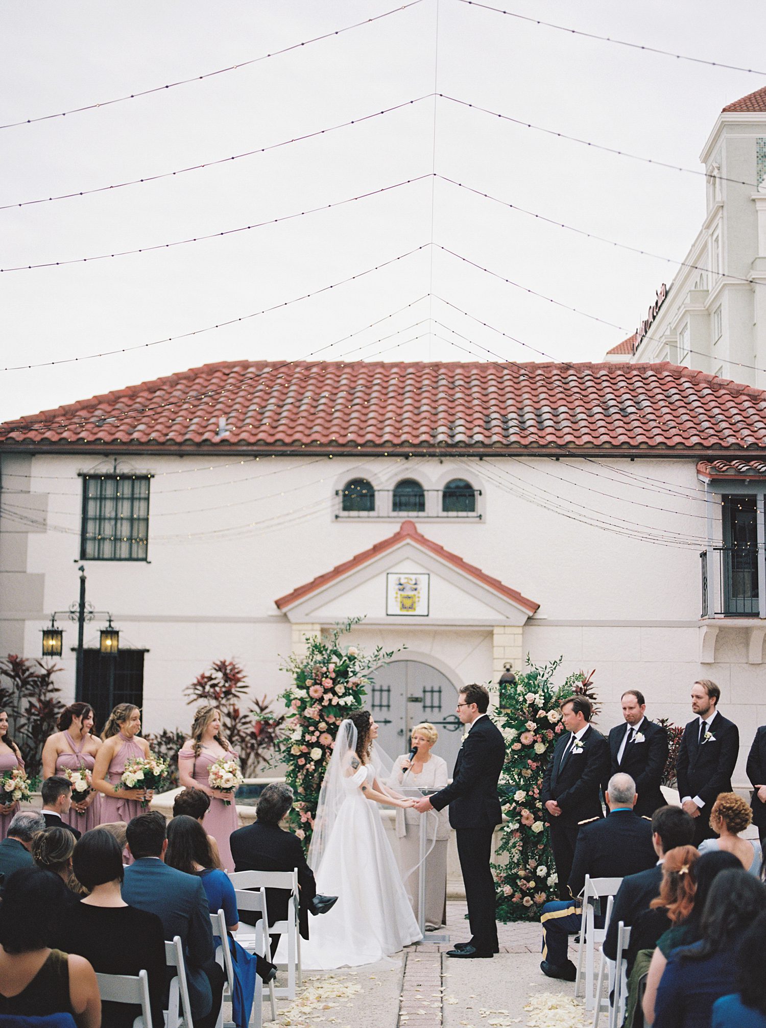 newlyweds hold hands in courtyard during ceremony