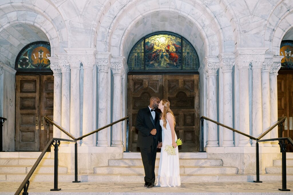 newlyweds kiss on stairs outside of church