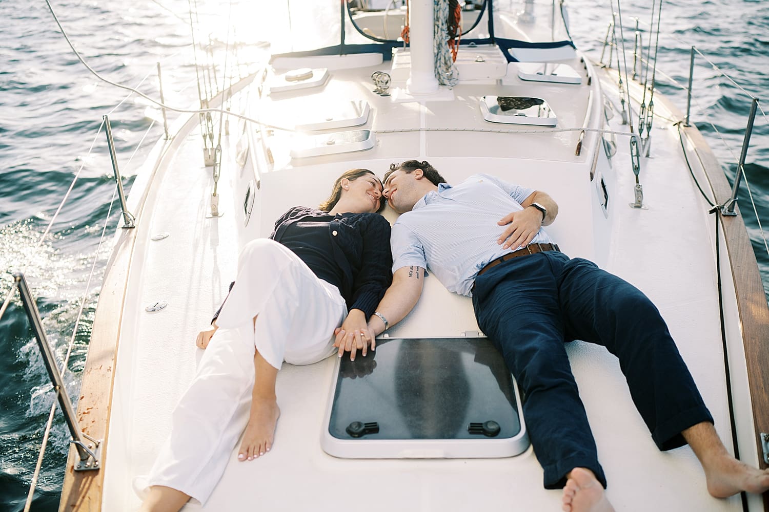couple kiss while laying next to each other on saliboat