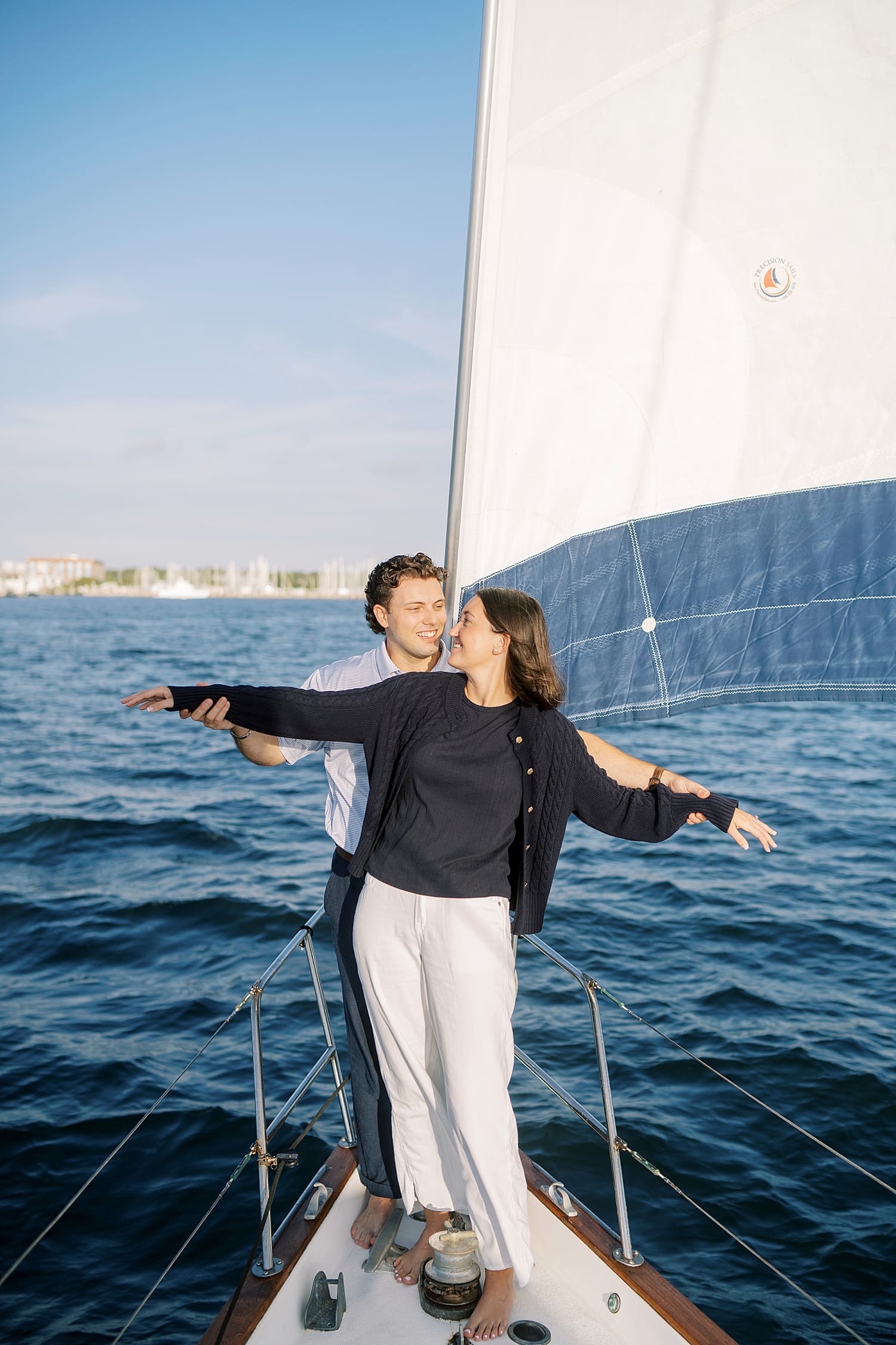 couple stand at bow of sailboat during Florida sailboat engagement session