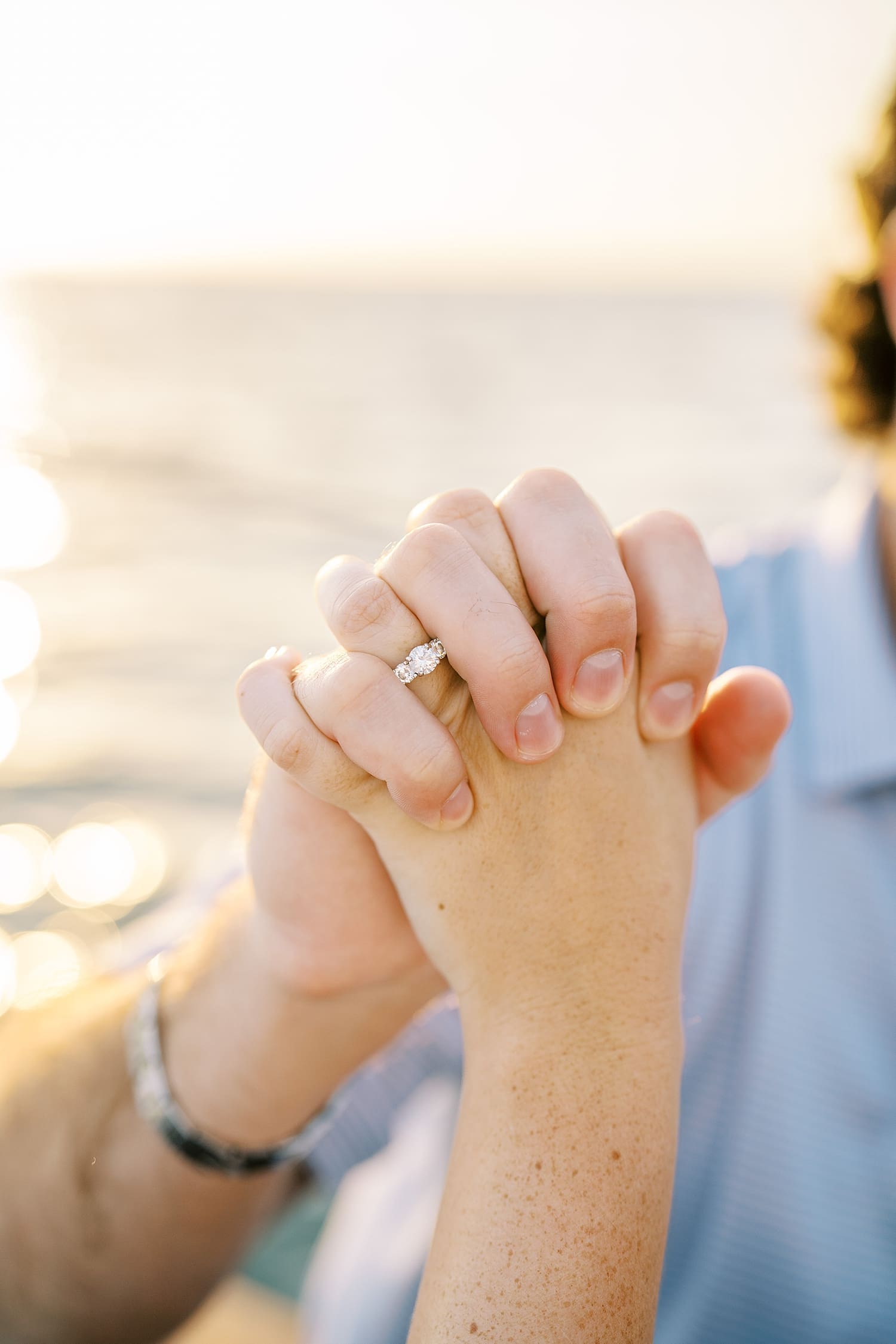 couple hold hands showing off engagement ring from Romantic Sunrise Sailboat Engagement Session in Tampa, FL