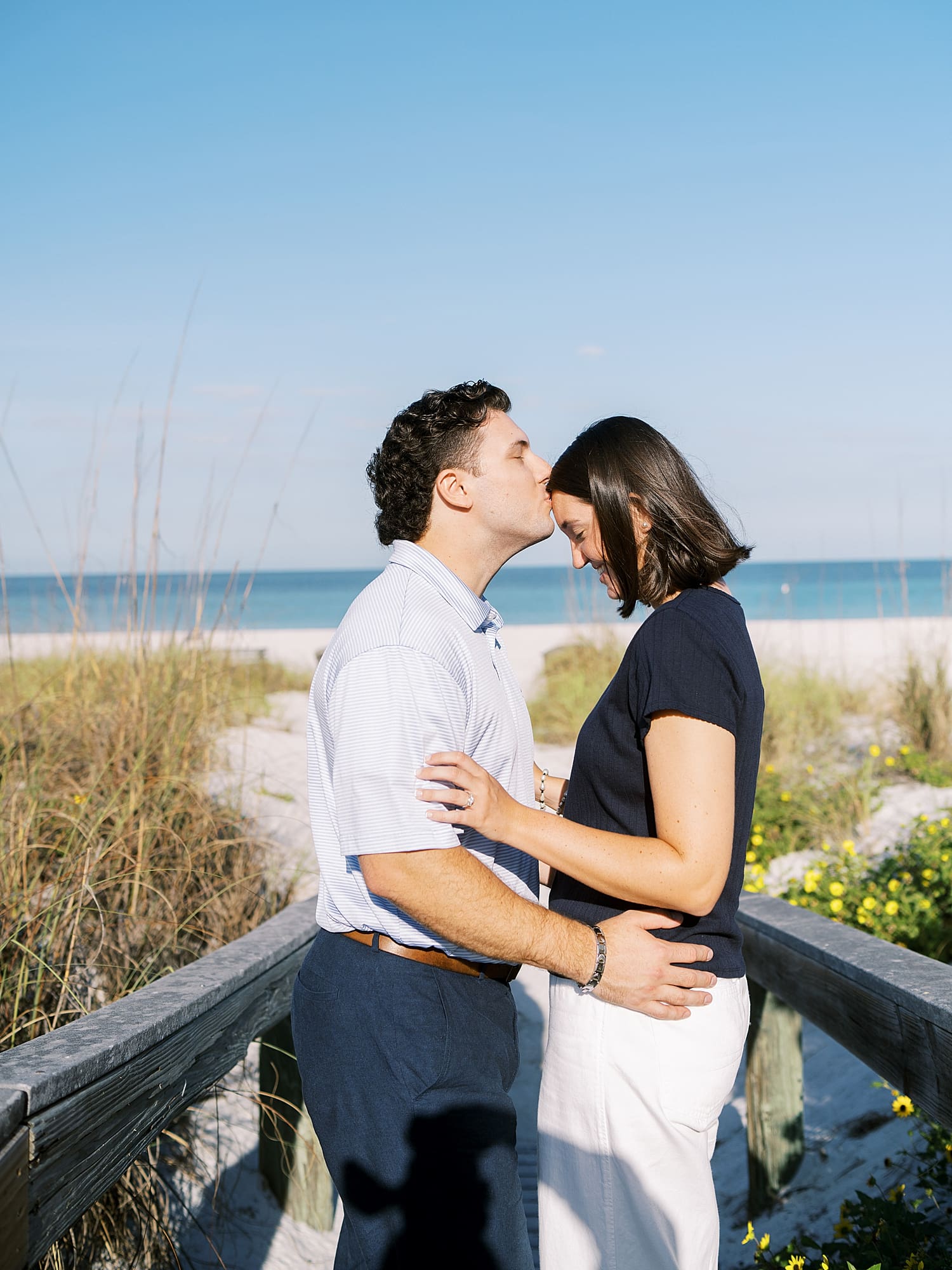 man kisses fiancé's head at Tampa Beach engagement session