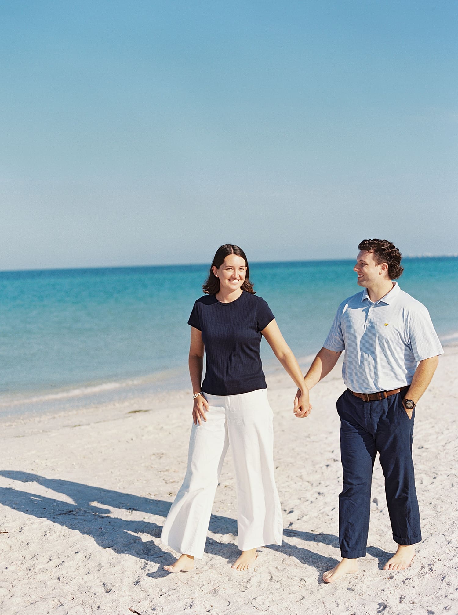 Engagement photos of couple holding hands at Pass a Grille Beach
