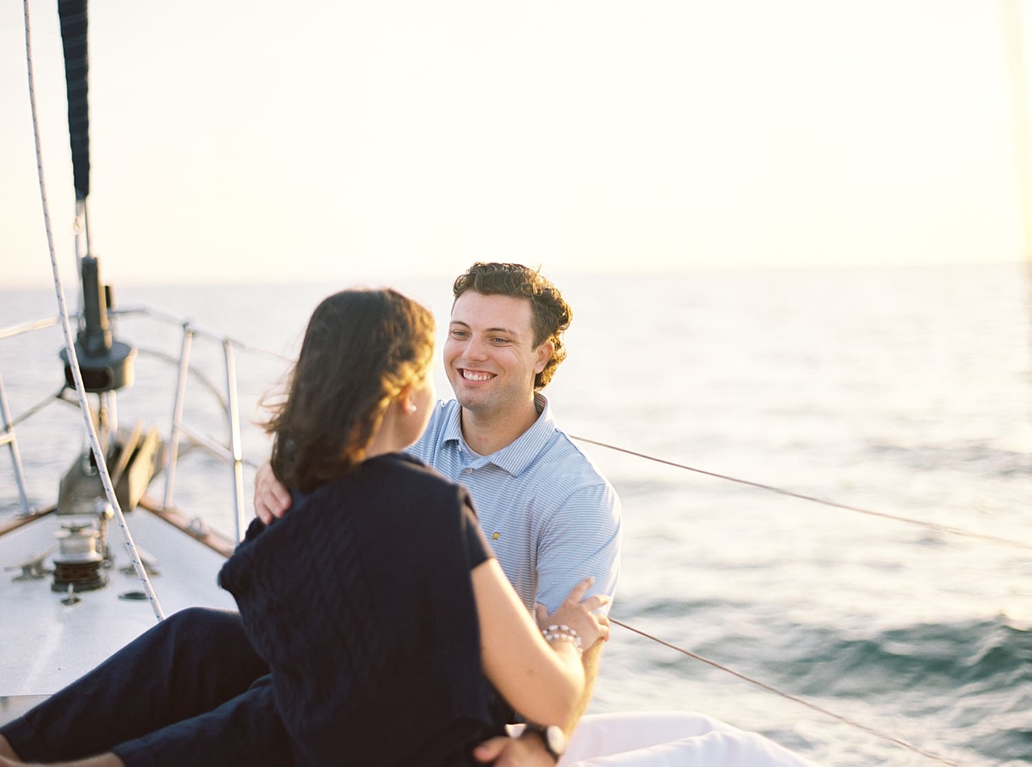 couple hug by the side of sailboat during engagement session