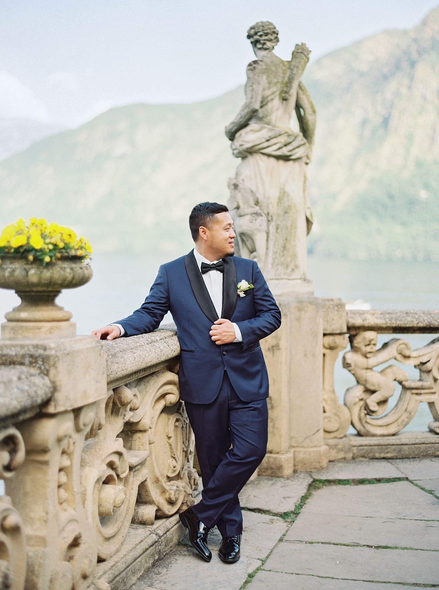 groom stands by scultpure at Villa del Balbianello 