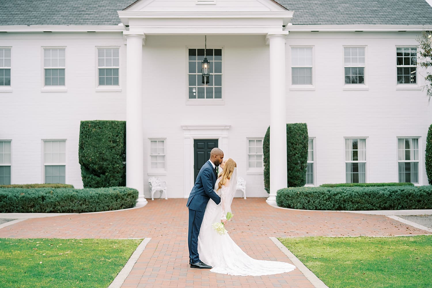 bride and groom kiss in front of Adams Estate, a central Florida venue