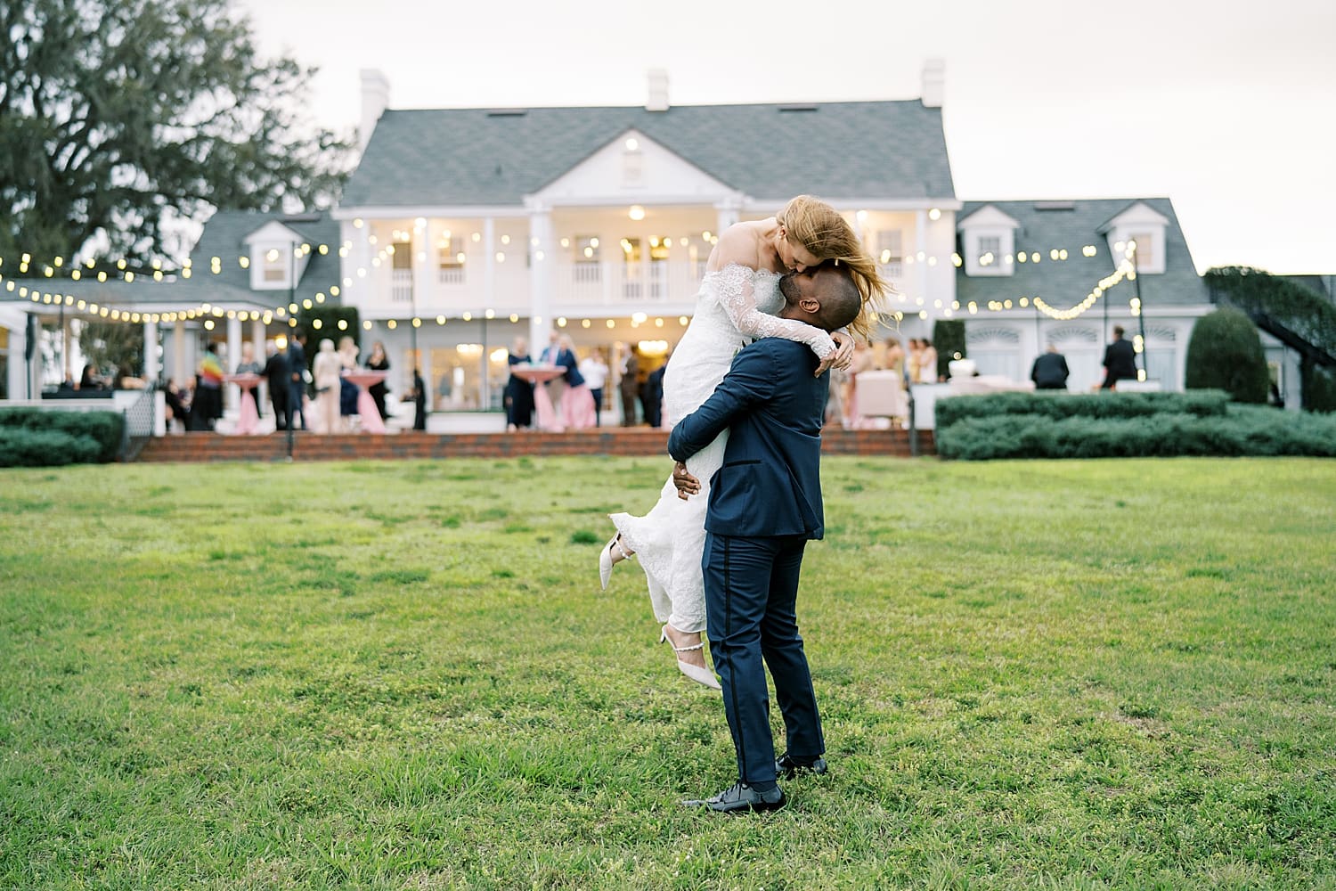 candid newlywed portraits of groom holding his bride up in his arms as they kiss