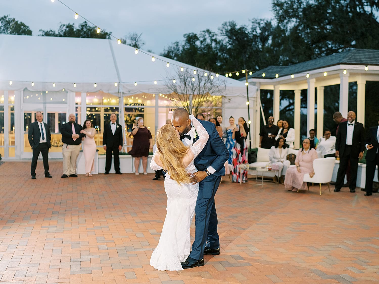 groom kisses bride on dance floor during their first dance