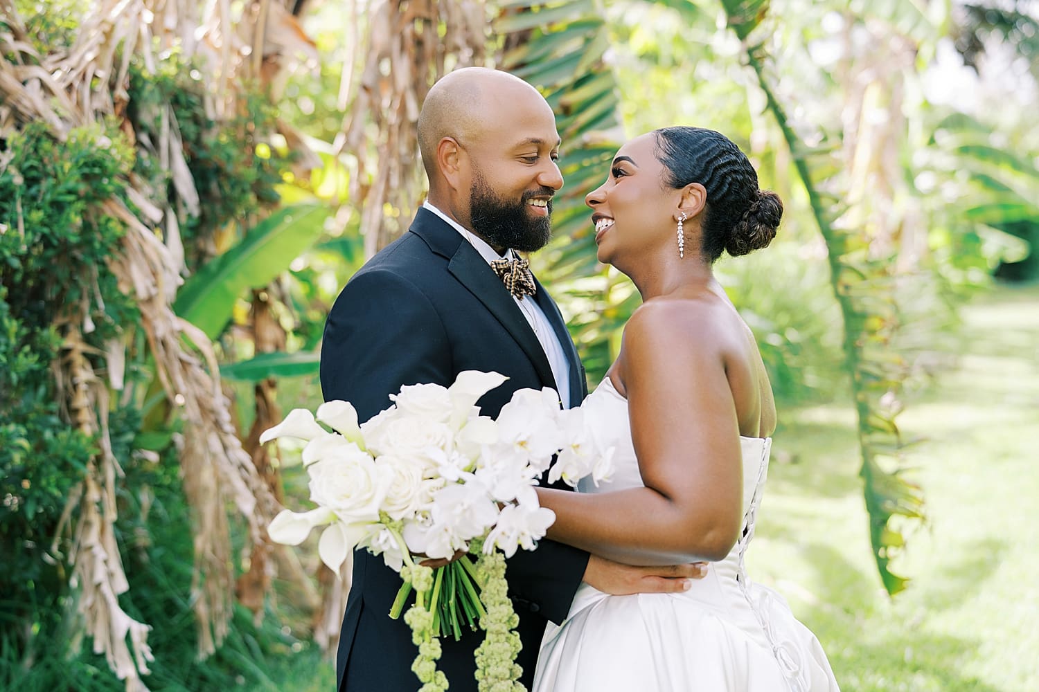 bride and groom lean in together by palm trees