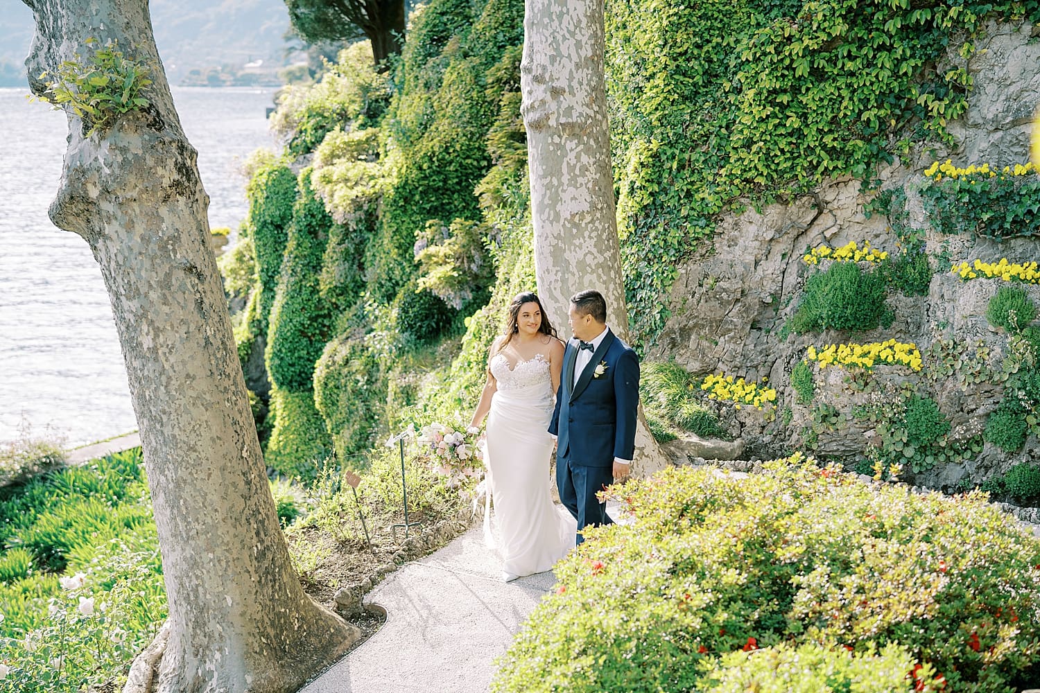 Newlyweds walk the property at Villa del Balbianello that features greenery and gardens
