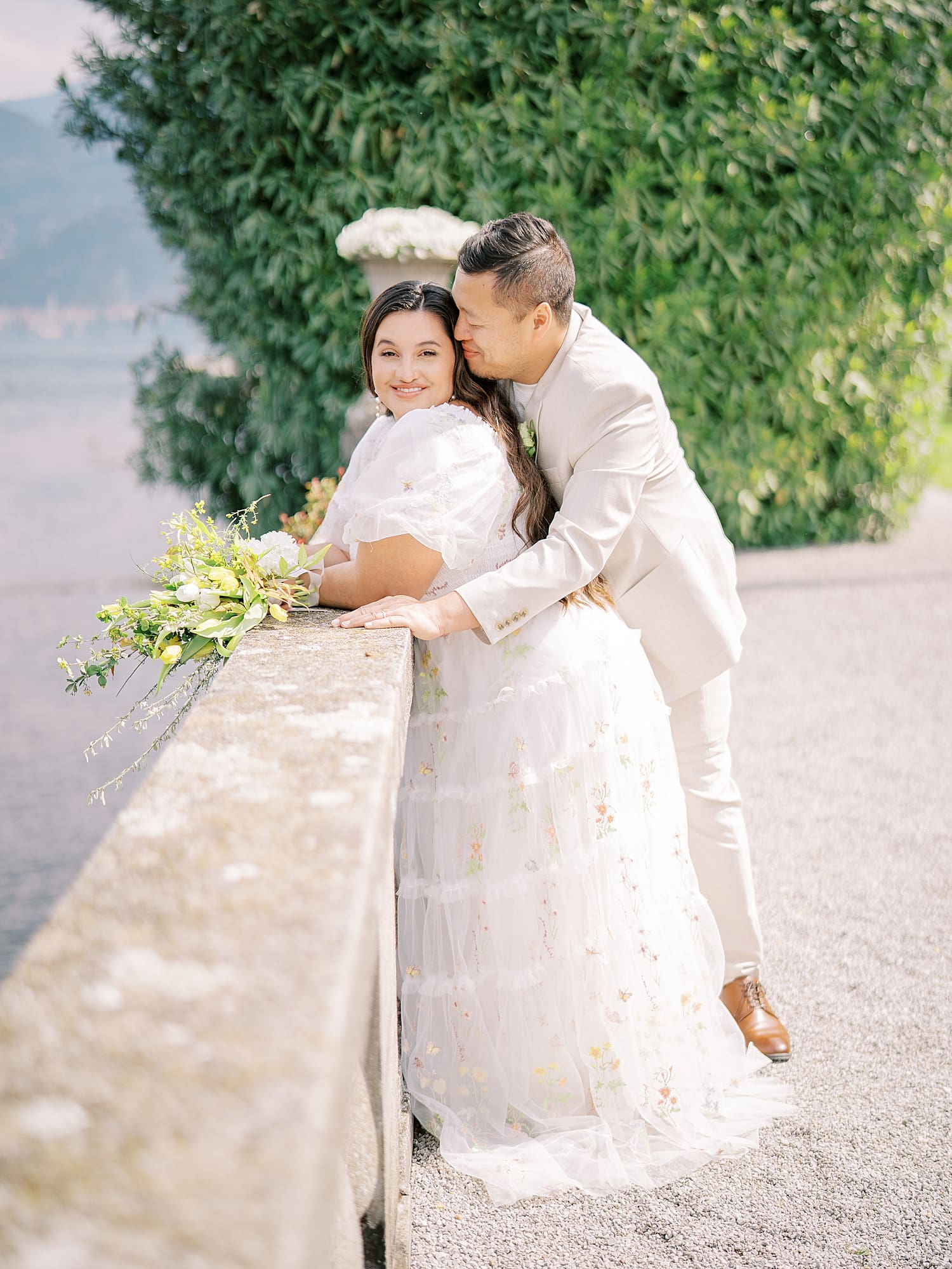 newlyweds lean over ledge of balcony at Villa Serbelloni