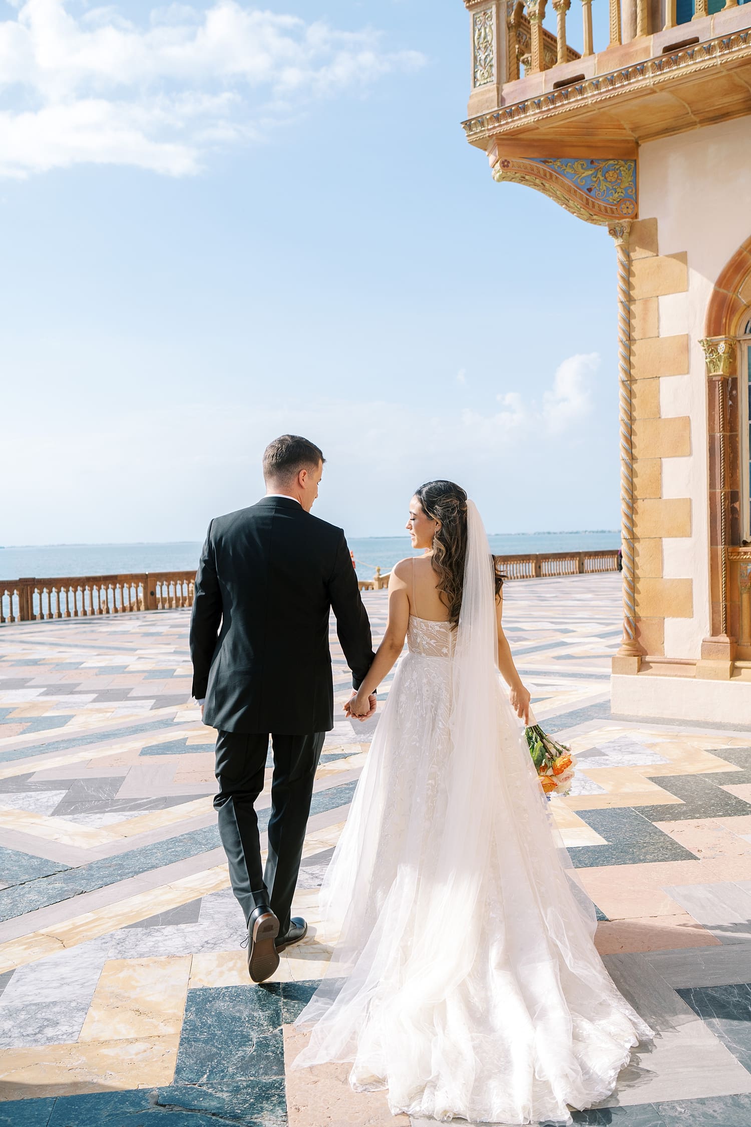 couple hold hands at The Ringling Museum wedding with waterfront views of the Sarasota bay 